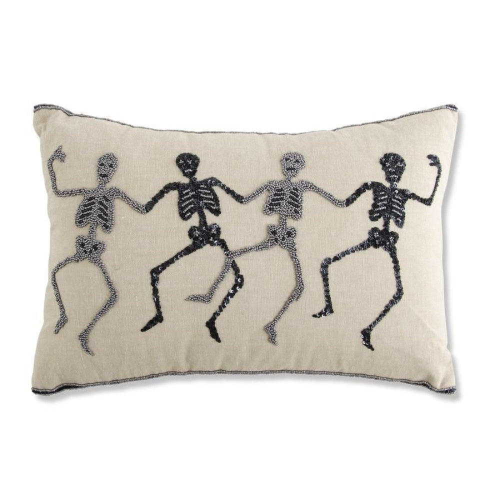 Beaded throw pillow featuring four dancing skeletons in a row against a beige fabric background.