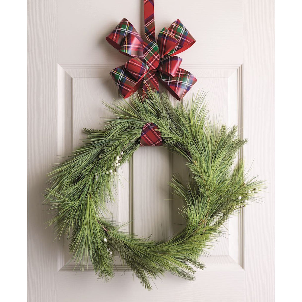 Red tartan plaid metal bow hanger holding a pine wreath on a white door.