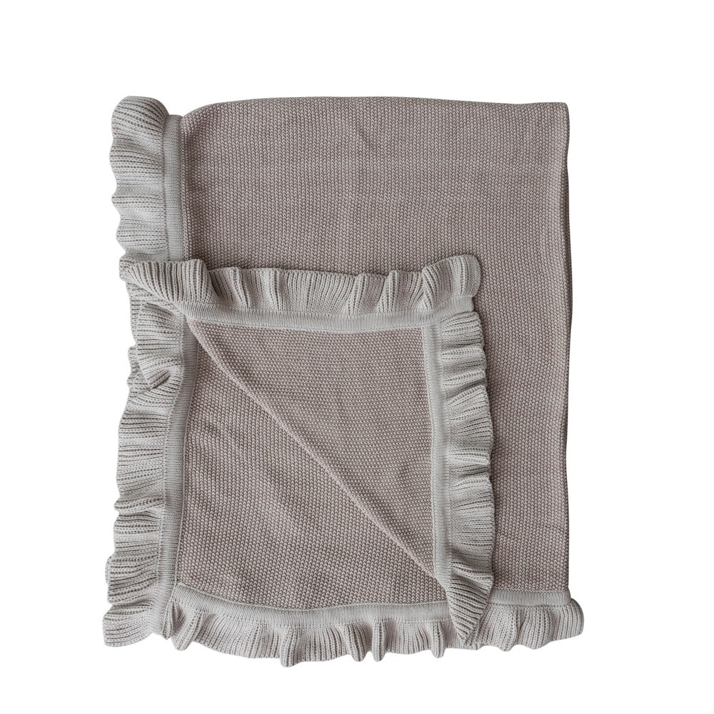 Folded taupe cotton knit throw blanket with ruffle edge detailing.