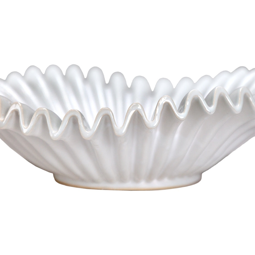 Close-up of a white ceramic bowl featuring a wavy, ruffled rim and vertical fluted texture.