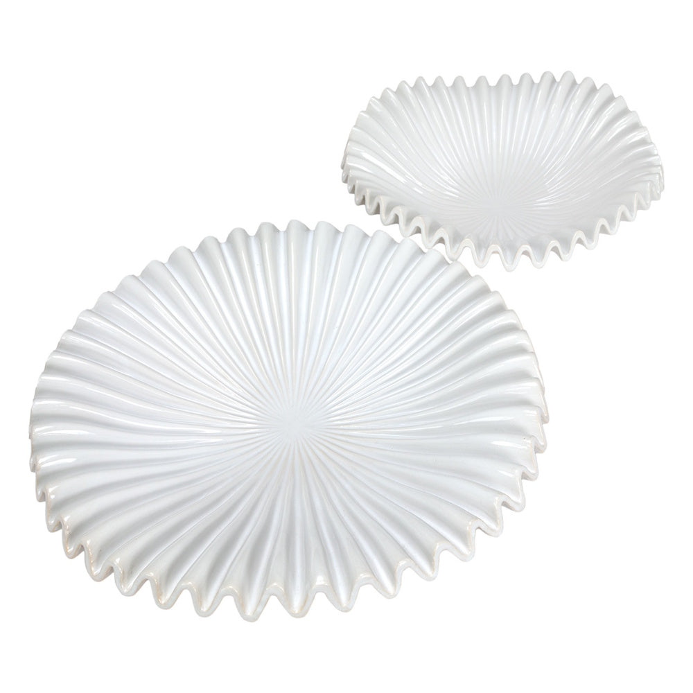 Two white fluted ceramic plates with scalloped edges and sunburst ridges on a white background.
