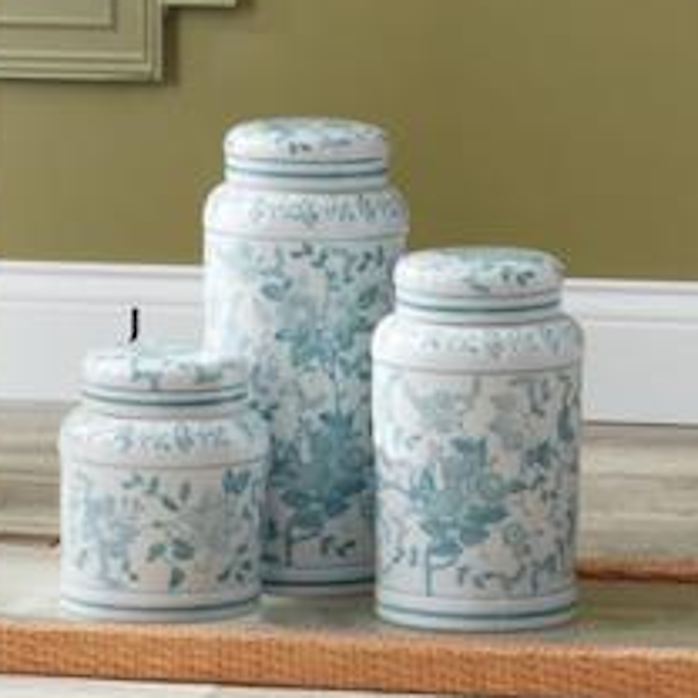 Set of three teal and white porcelain chinoiserie jars in various sizes with floral patterns on a wooden surface.