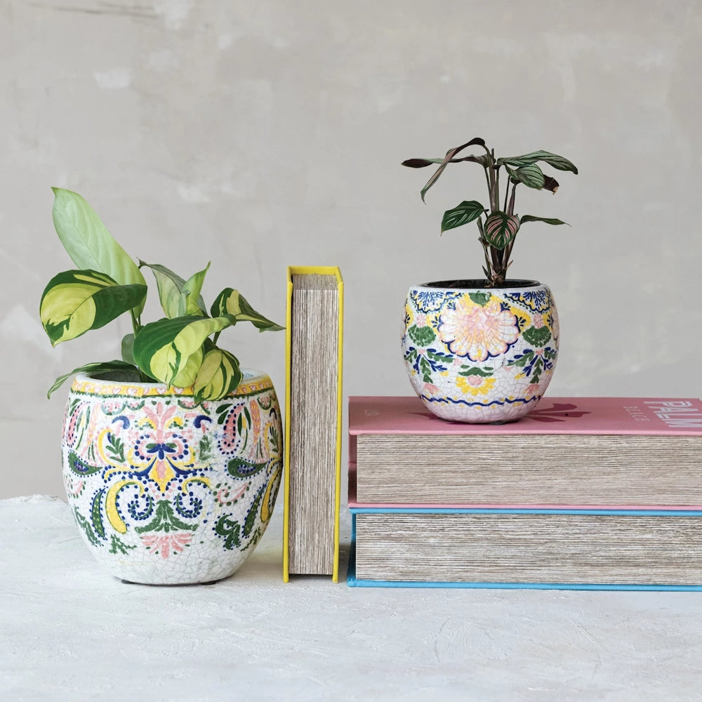 Decorative mosaic planter pots with green houseplants sitting on books, ideal for bohemian home office shelf decor.