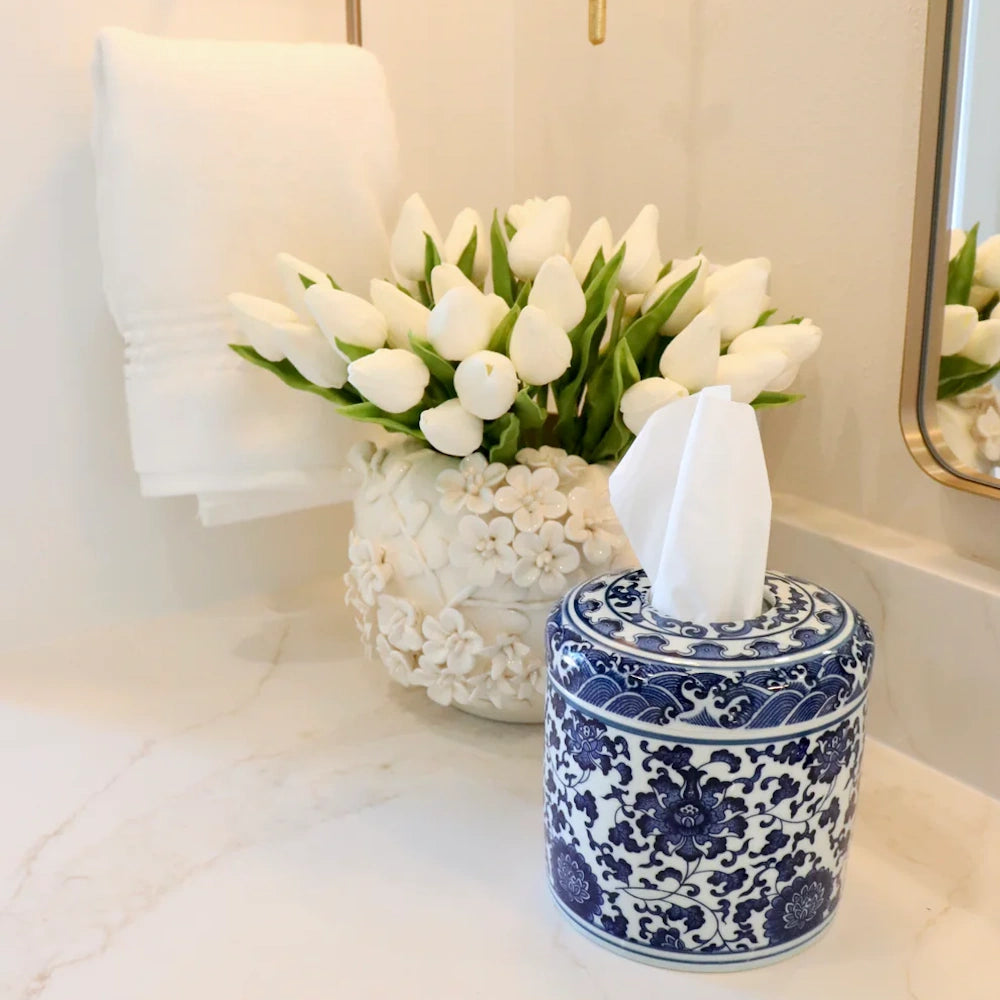 Blue and white floral chinoiserie tissue canister next to a white tulip arrangement in a textured floral vase.