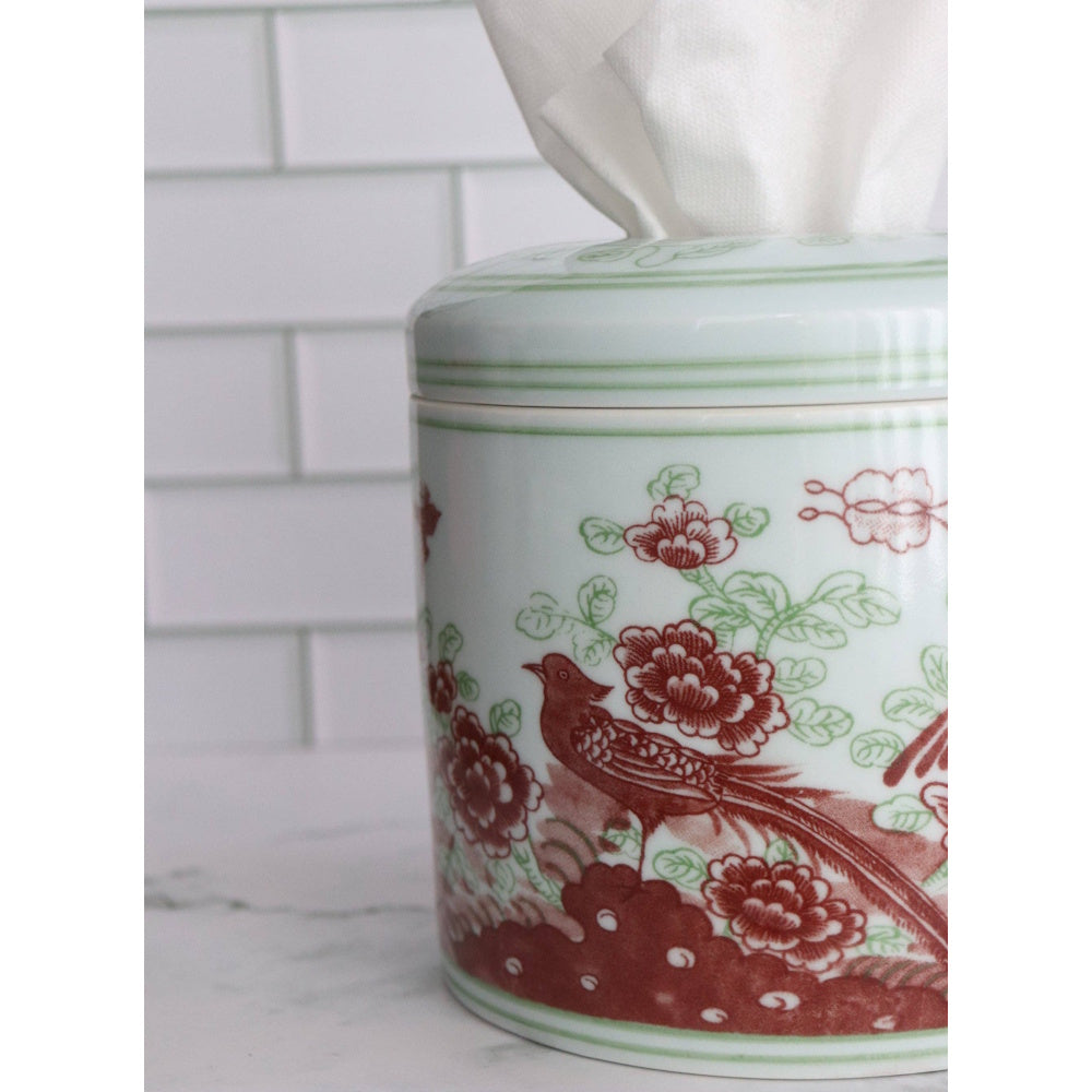 Close-up of a porcelain tissue vessel featuring a red floral and bird pattern against white tiles.