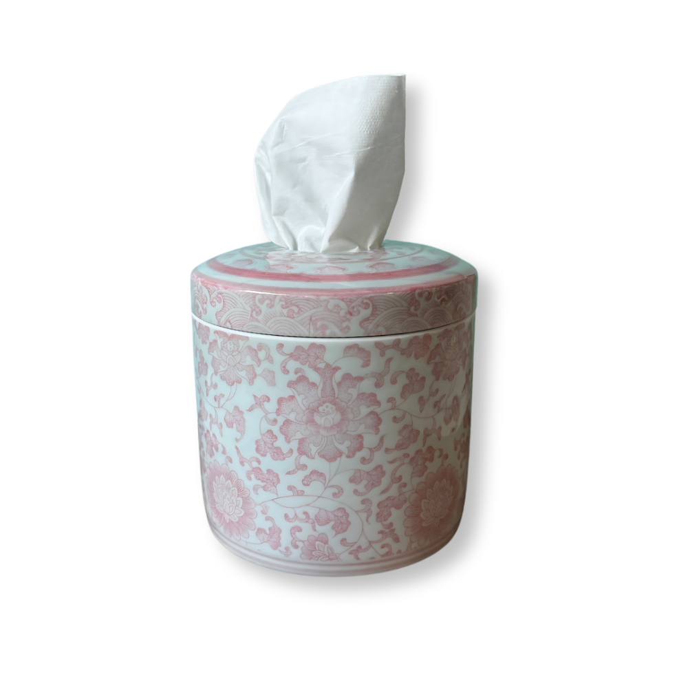 Pink and white floral ceramic tissue canister with a white tissue emerging from the top, isolated on a white background.
