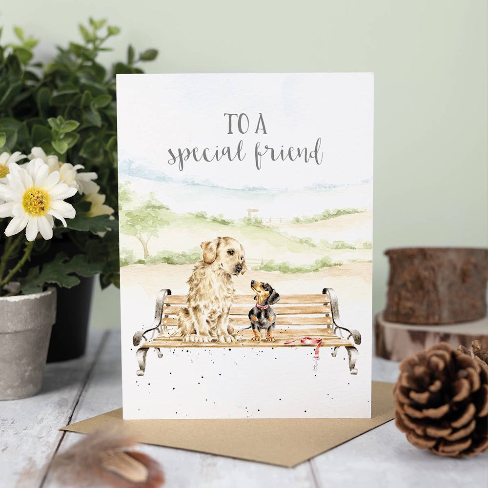 Greeting card featuring two dogs on a park bench with the text "To a special friend" in a watercolor style.
