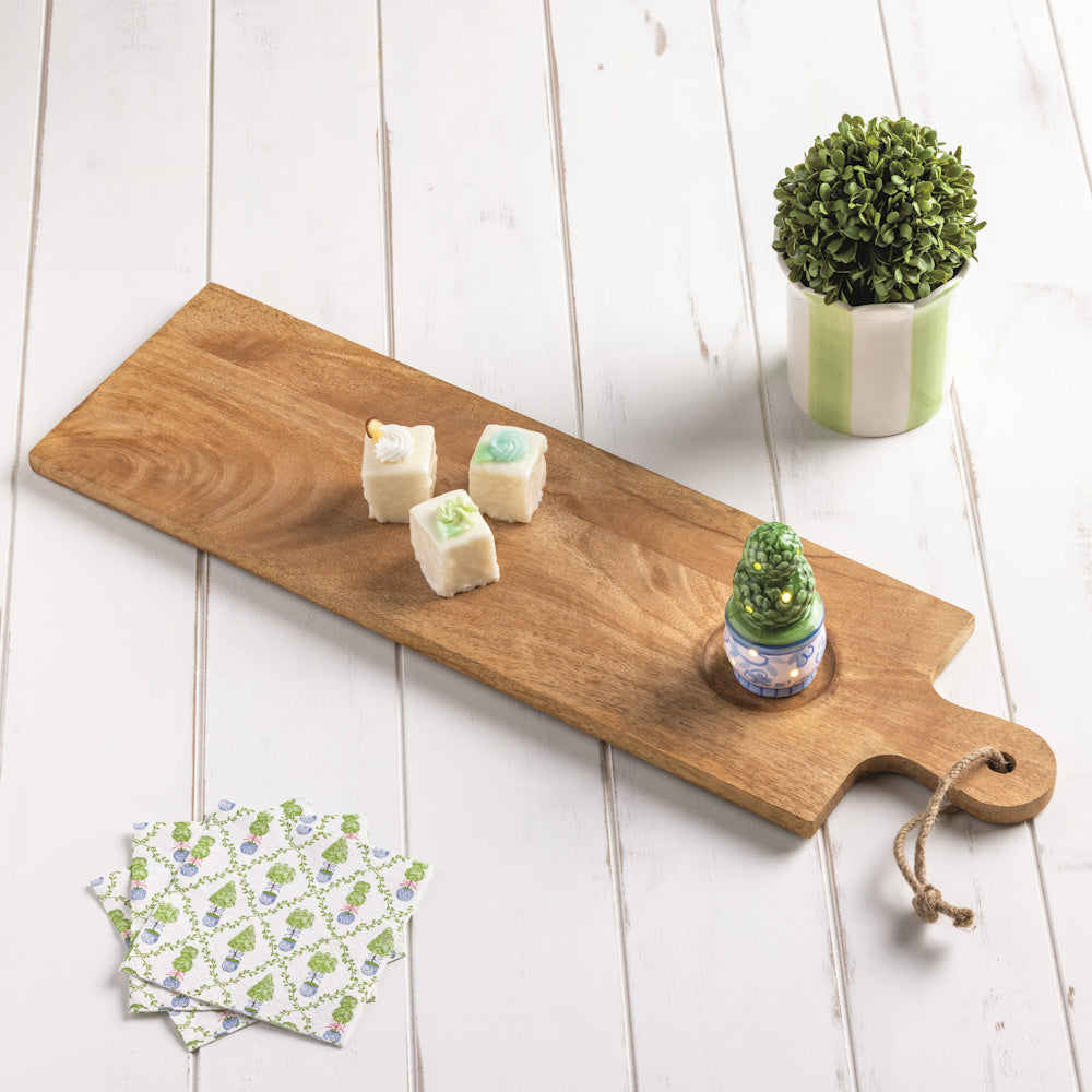 Topiary LED sitter and petit fours on a wooden serving board with matching napkins and a potted boxwood plant.