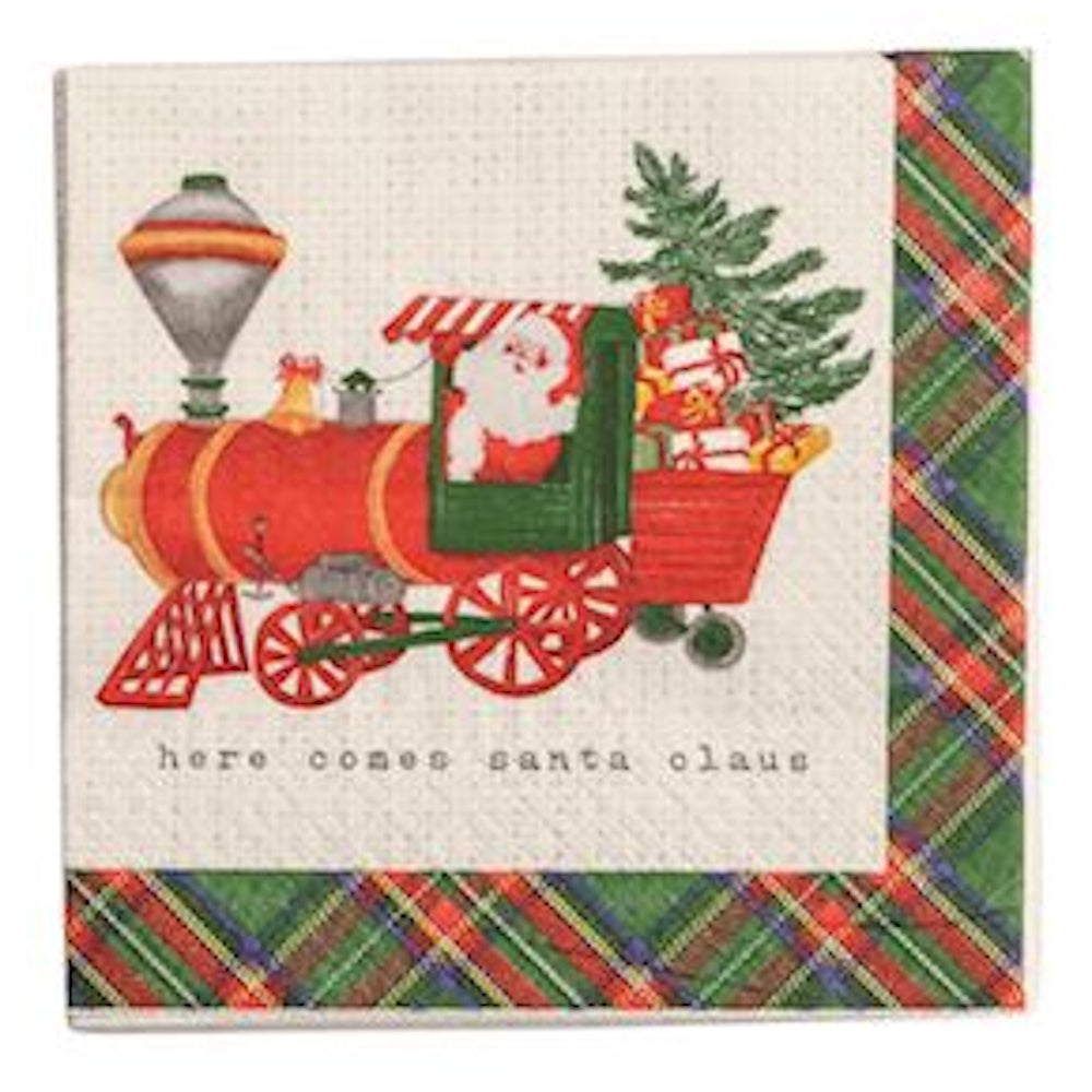 Square cocktail napkin depicting Santa Claus driving a red toy train loaded with gifts, framed by a plaid border and captioned "here comes santa claus."