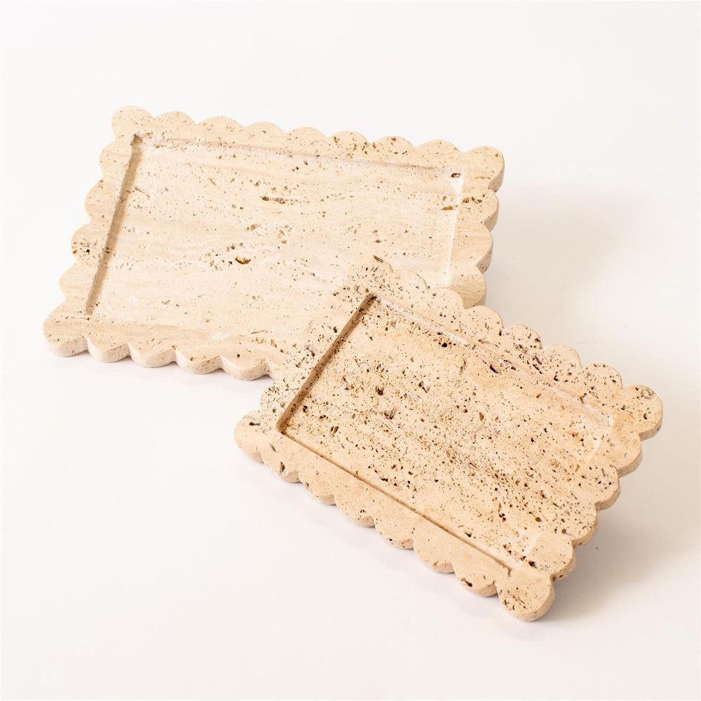 Two scalloped beige travertine stone decorative trays on a white background, featuring natural porous texture and pits.
