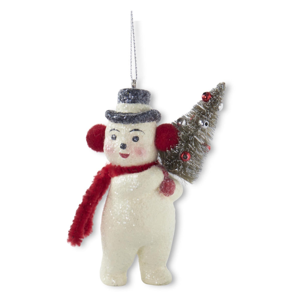 A hanging glittered snowman ornament wearing earmuffs, a scarf, and a top hat while carrying a small bottle brush tree.