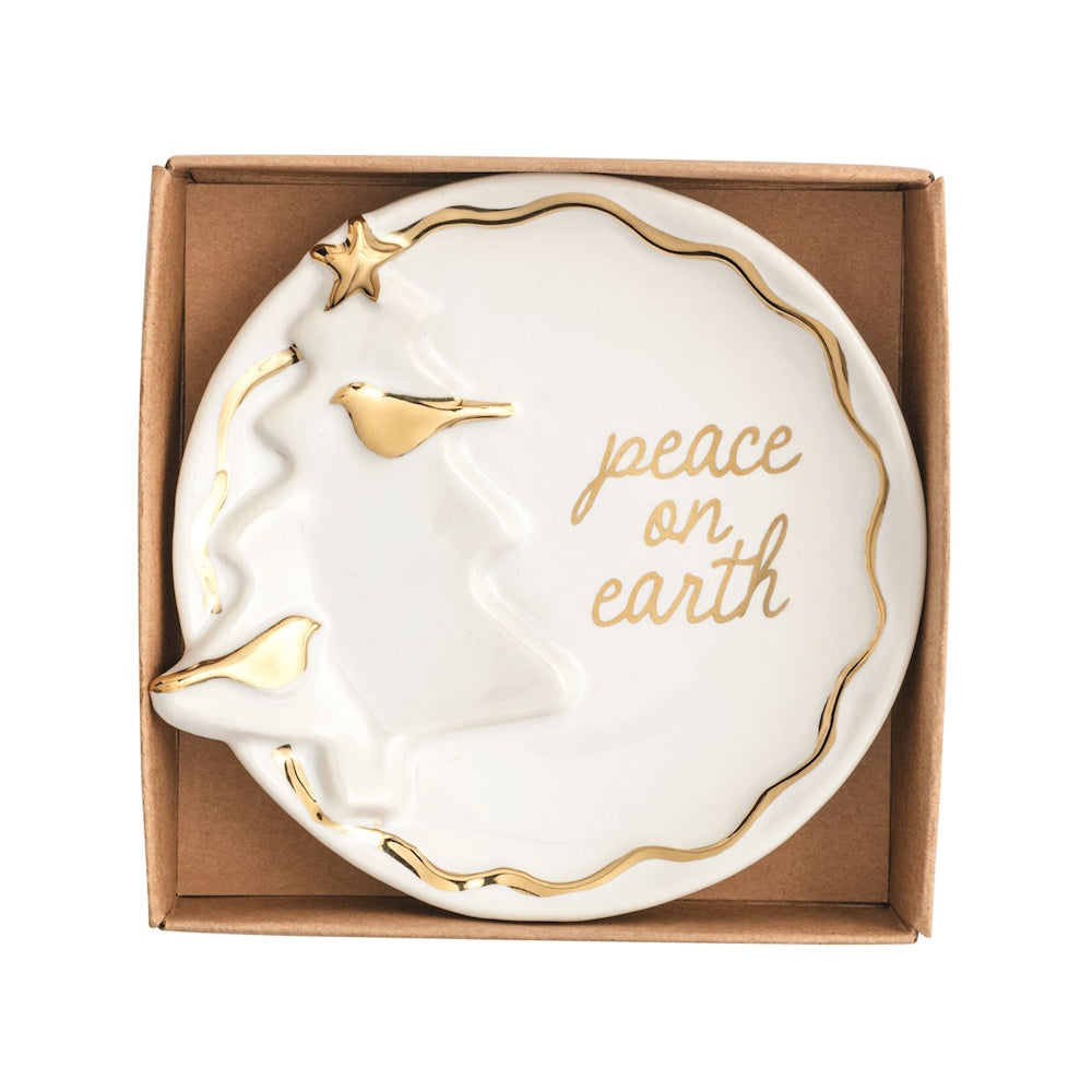 White ceramic trinket dish featuring gold accents, a tree design, and "peace on earth" text in a box.