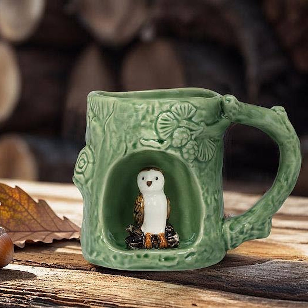 Green ceramic tree trunk mug featuring a small barn owl figurine nestled inside a hollow niche.