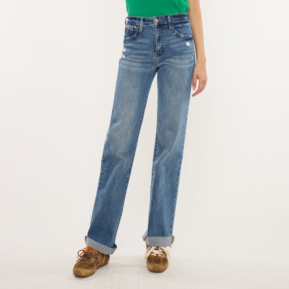 High-rise straight-leg blue jeans with cuffed hems, slight distressing, and brown sneakers.