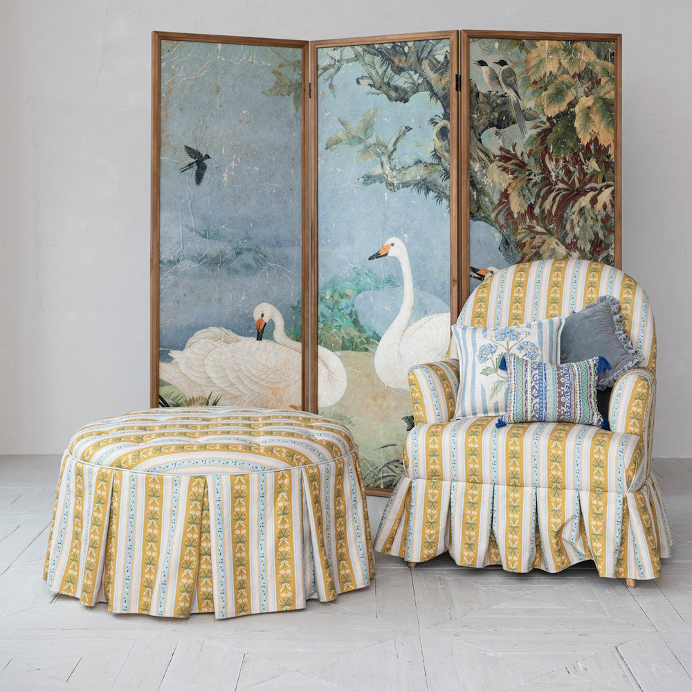 Yellow striped tufted ottoman and matching armchair with a box pleat skirt.