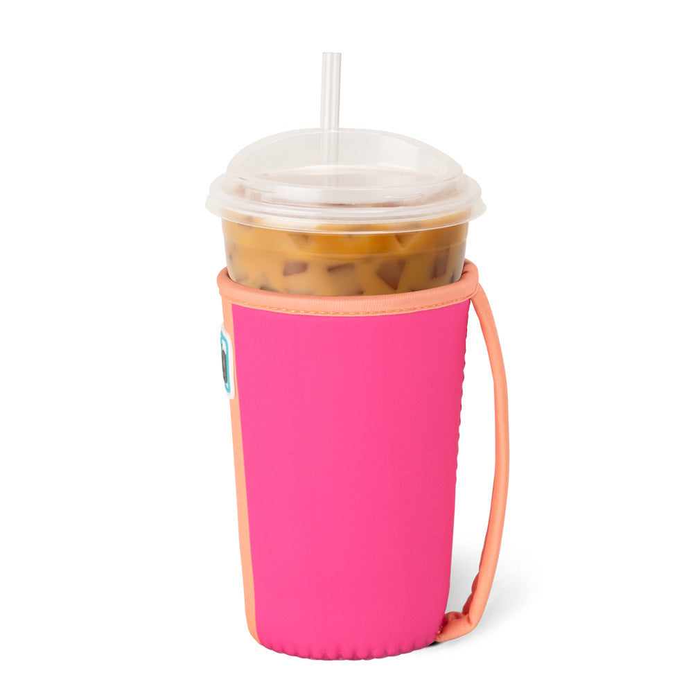 An iced coffee cup in a vibrant pink and peach neoprene sleeve with a built-in handle and a straw.