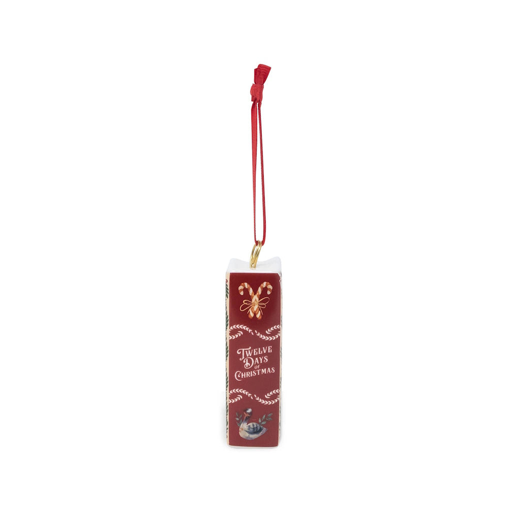 Side view of a "Twelve Days of Christmas" ceramic book ornament hanging from a red ribbon.