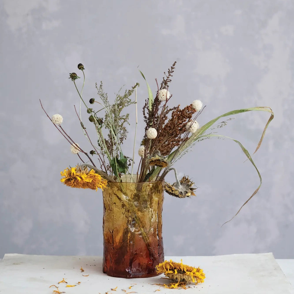 Two-tone amber textured glass vase holding a arrangement of dried wildflowers and sunflowers.