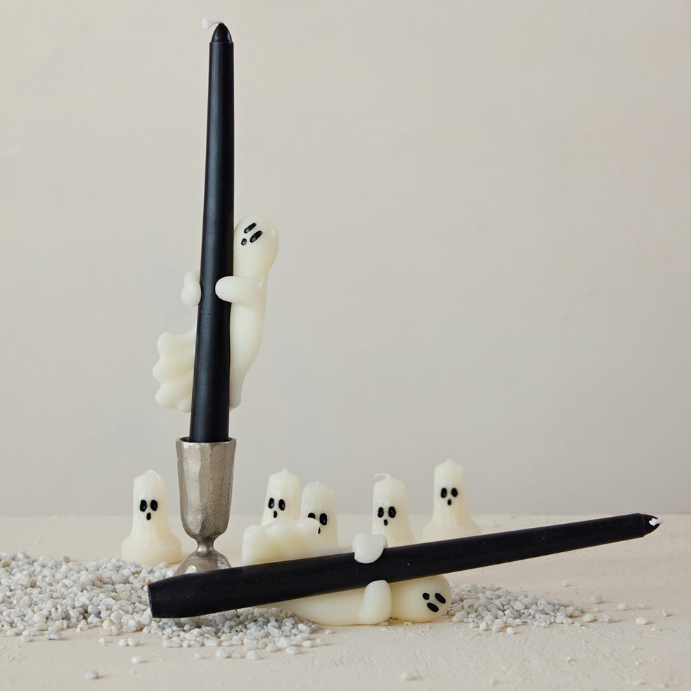Black taper candles held by cute ghost figures, surrounded by mini ghost candles.