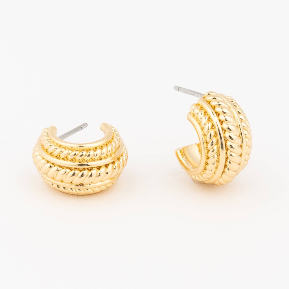 Pair of gold textured huggie hoop earrings on a plain white background.