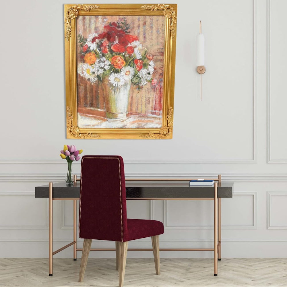 Vintage floral painting in an ornate gold frame hanging above a modern desk with a burgundy velvet chair.