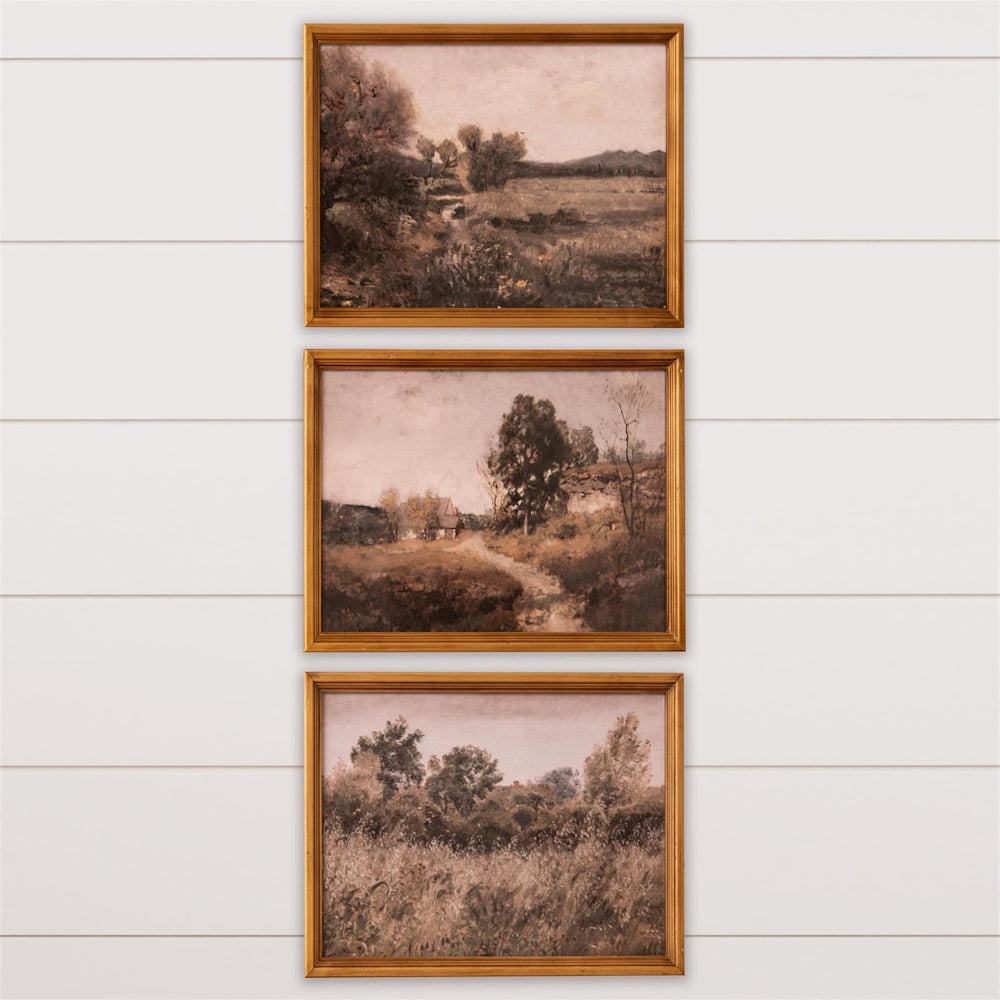 Set of three vintage landscape art prints in antique gold frames hanging on a white shiplap wall.