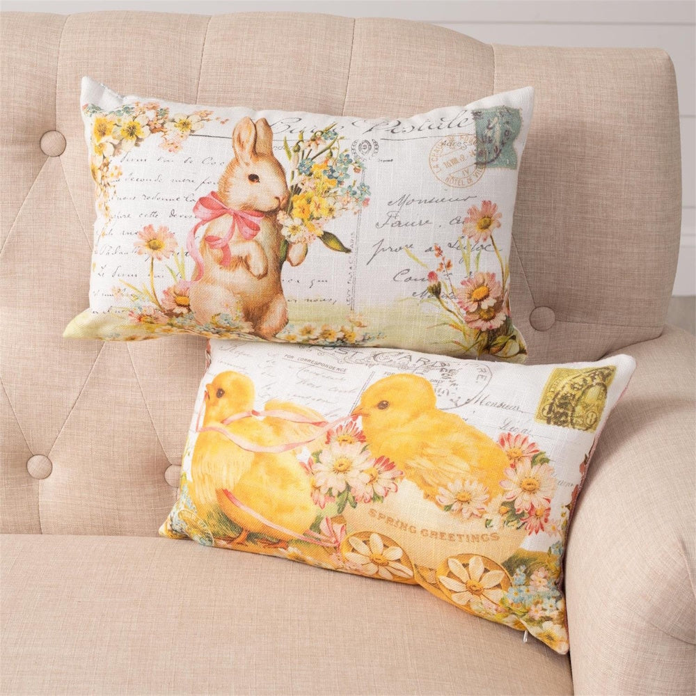 Two Easter throw pillows with vintage postcard designs featuring a bunny and yellow chicks on a beige armchair.