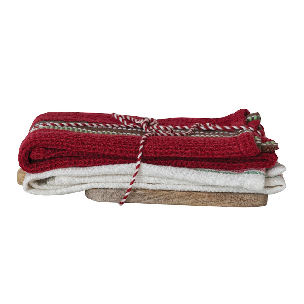 Folded red and white waffle kitchen towels tied with twine on a wooden board.
