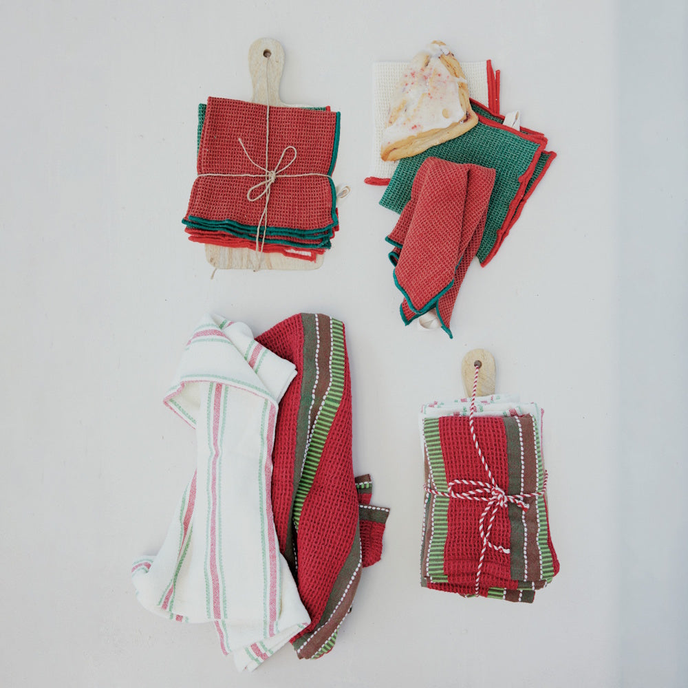 Red and green waffle-weave tea towels arranged with wooden serving boards on a white surface.