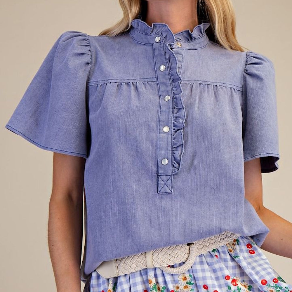 Washed blue chambray short-sleeve top featuring ruffled collar, placket detail, and pearl buttons.