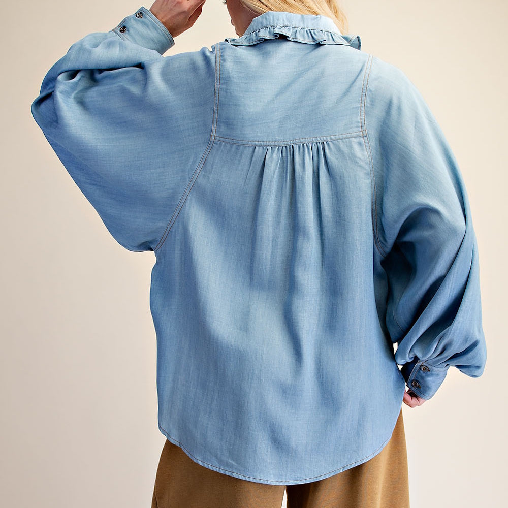 Back view of light blue washed denim chambray shirt featuring a ruffled collar and gathered back yoke.