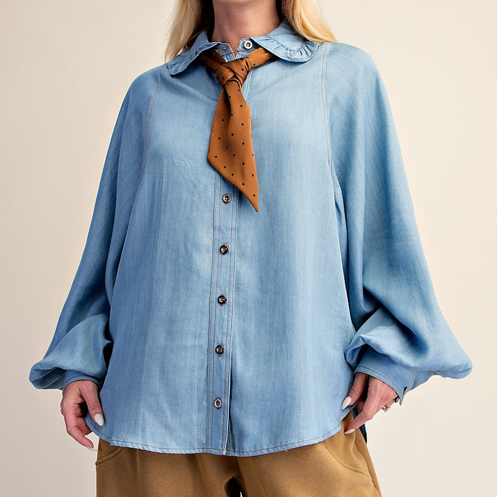 Light blue washed denim chambray button-down shirt styled with a tied brown patterned neck scarf.