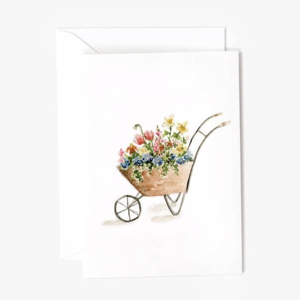 Watercolor illustration of a wheelbarrow filled with colorful flowers on a white notecard.