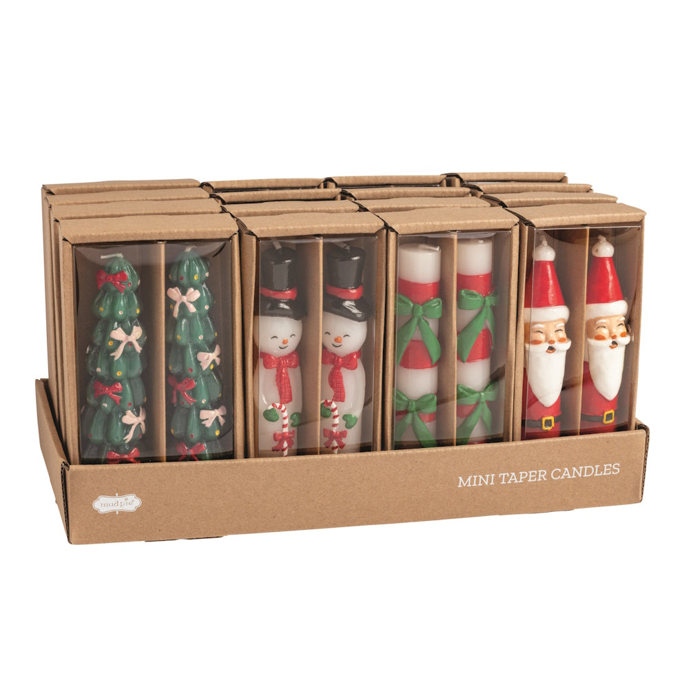Flat lay view of four assorted sets of colorful wax Christmas mini taper candles in brown cardboard boxes.