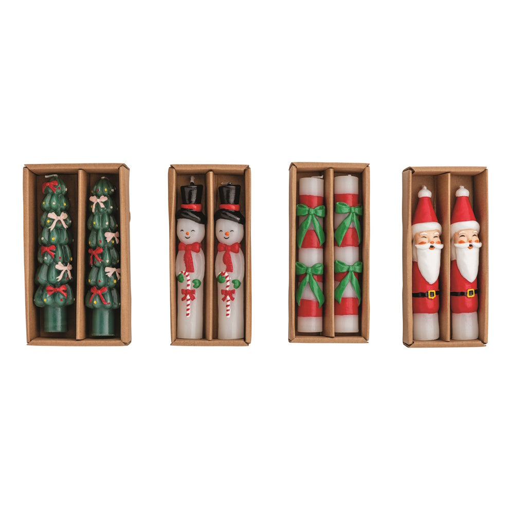 Flat lay view of four assorted sets of colorful wax Christmas mini taper candles in brown cardboard boxes.