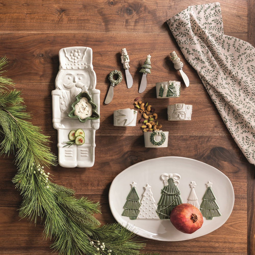 Lifestyle shot of a Christmas table setting with nutcracker serveware, holiday platters, and festive spread.