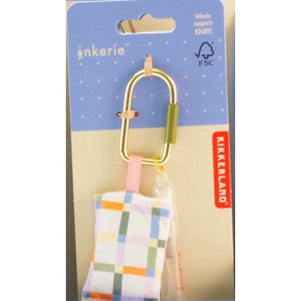 Inkerie on-the-go lens cleaning kit in packaging with a gold carabiner, plaid cloth pouch, and spray bottle.