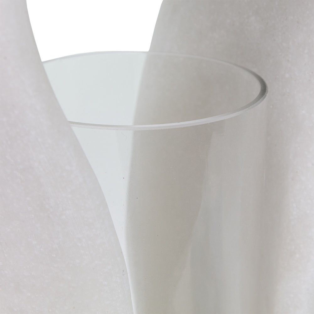 Close-up of a clear glass cylinder insert held by a sculpted white marble hurricane candle holder.