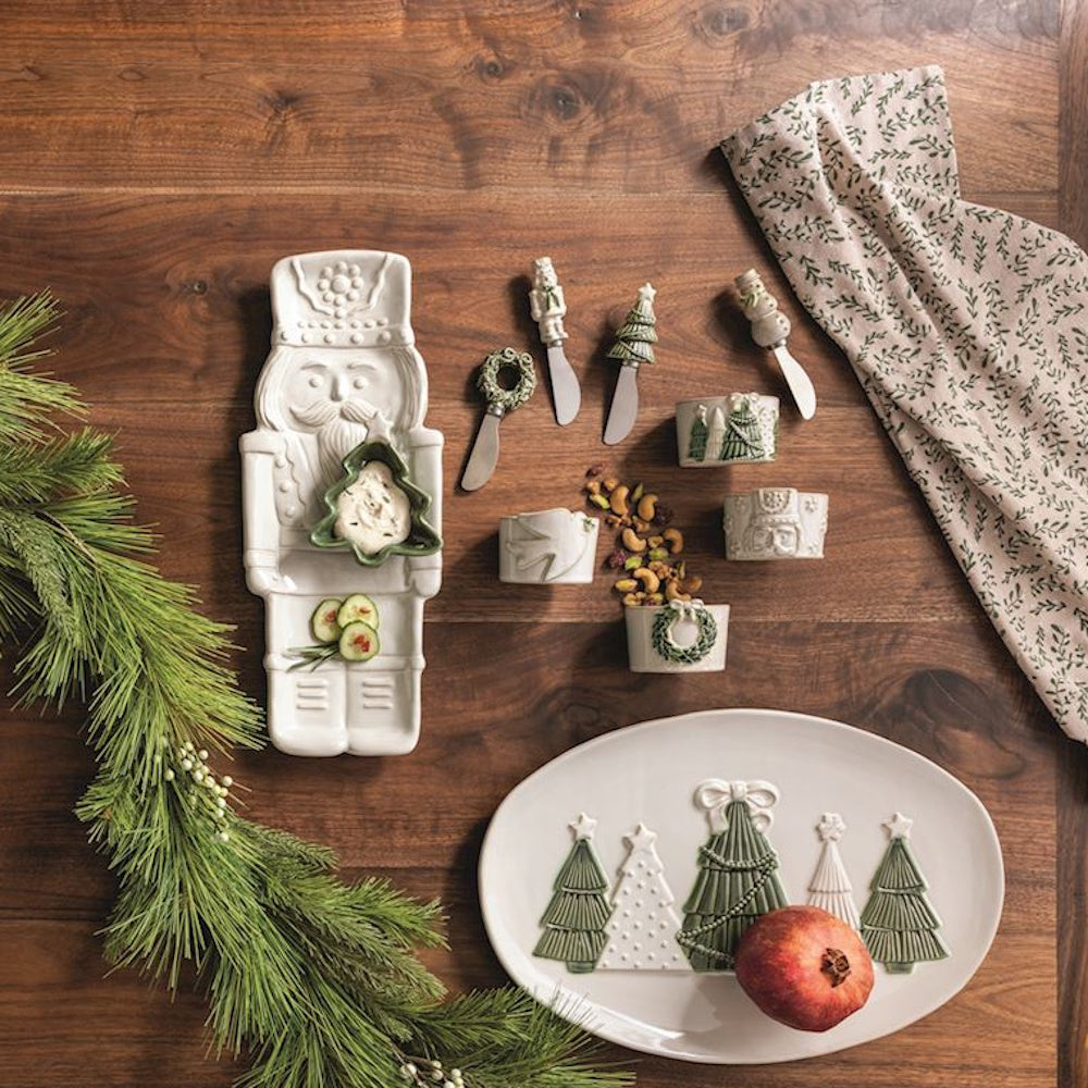 White nutcracker chip platter set on a wooden table with festive serveware and holiday greenery.