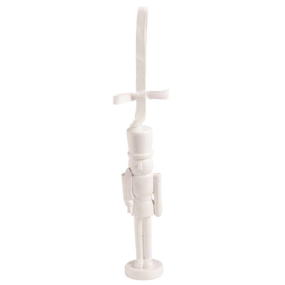 Glossy white nutcracker ornament hanging from a white ribbon with a bow on a white background.