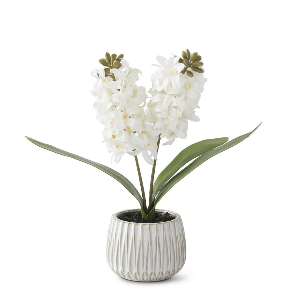 White hyacinth artificial plant in a ribbed white ceramic pot with faux dirt on a white background.