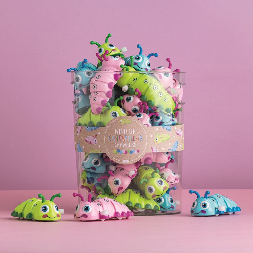 Colorful wind-up caterpillar crawler toys in a clear display jar with green, pink, and blue options on a pink background.