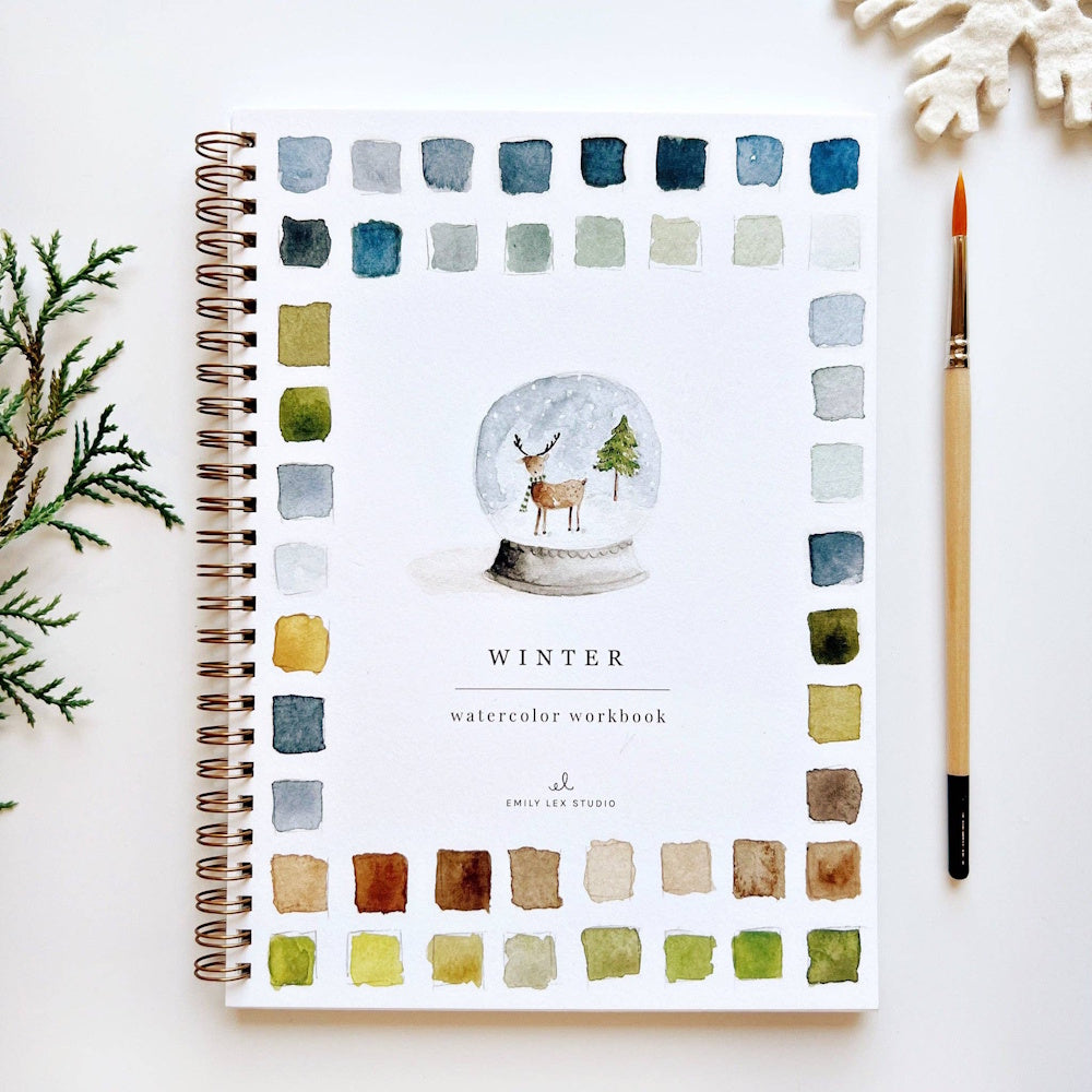 Winter watercolor workbook with color swatches, a snow globe illustration, and a paintbrush.