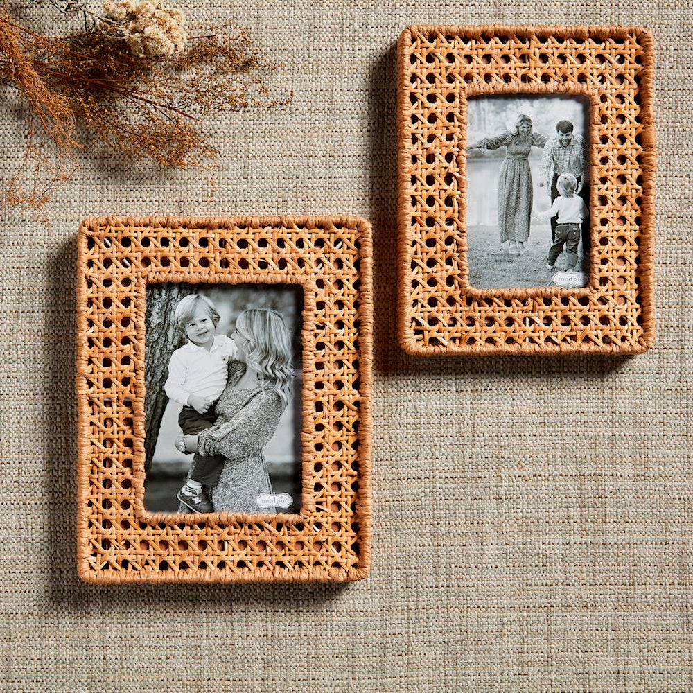 Two woven cane picture frames featuring black and white family photos, displayed on a neutral textured background.