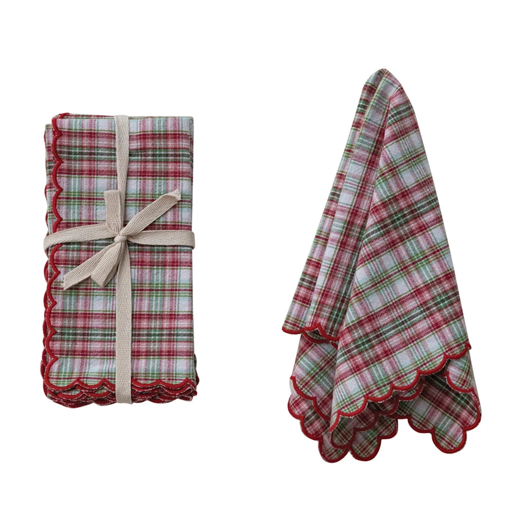 Red and green plaid napkins with scalloped edges, shown folded with a beige bow and draped on a white background.
