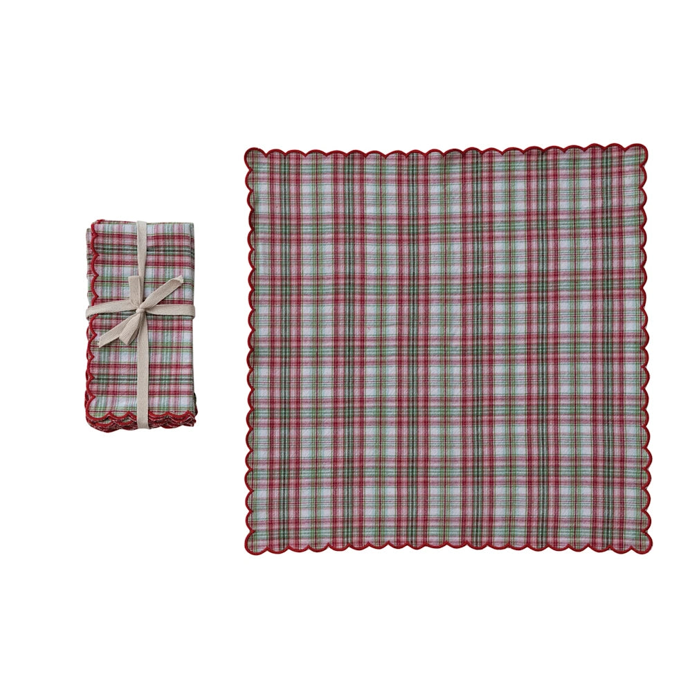 Red and green plaid napkin with scalloped edges, shown flat and folded with a beige bow on a white background.