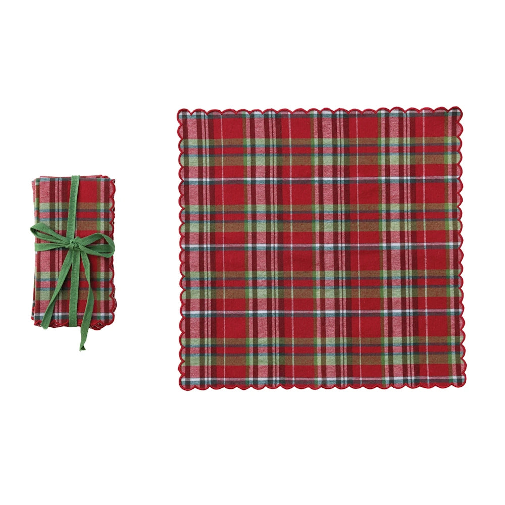 Red tartan plaid napkin with scalloped edge shown flat and folded with a green bow on a white background.