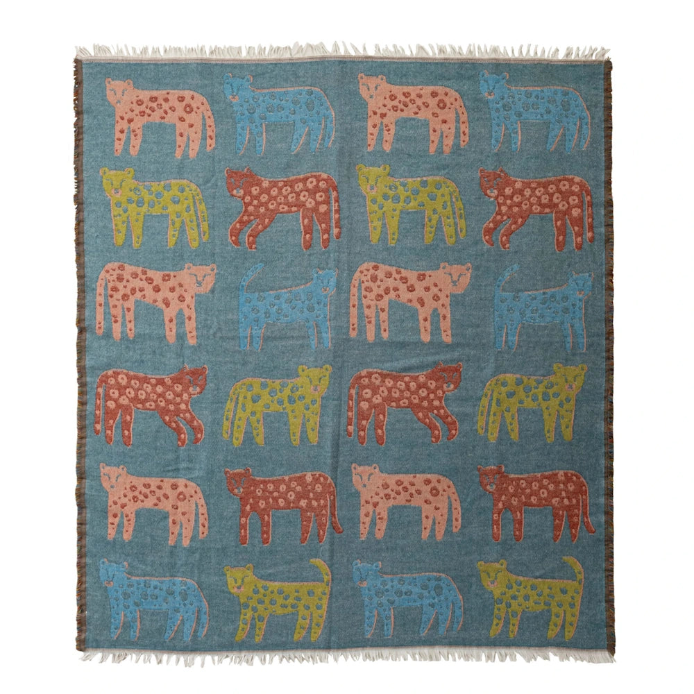 A teal woven throw blanket patterned with colorful spotted leopards and finished with fringe edges.