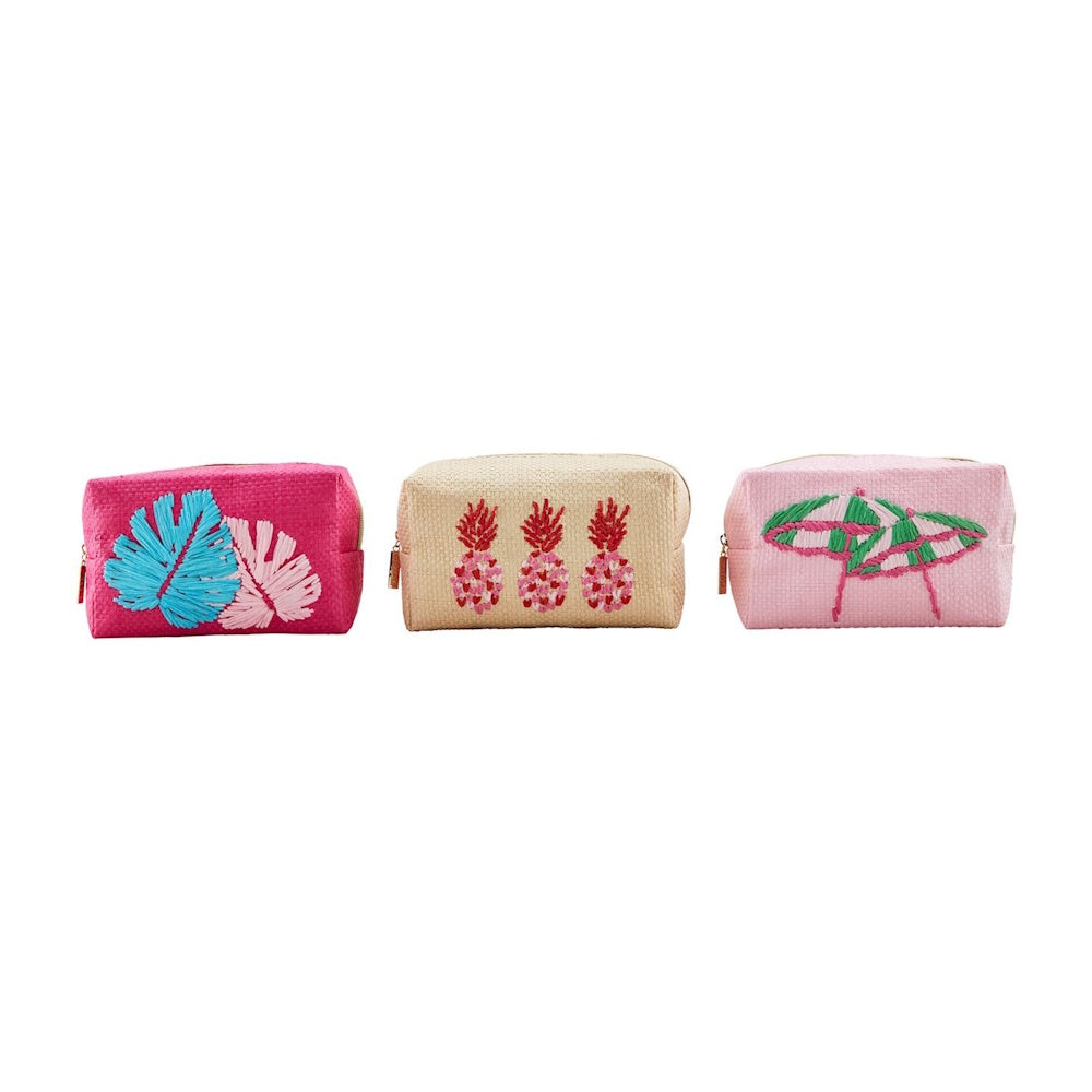 Three woven makeup bags with embroidered summer designs: monstera leaves, pineapples, and a beach umbrella.