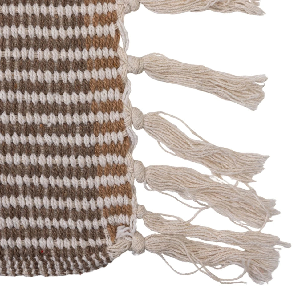 Textured woven throw detail with brown and cream stripes and decorative cream-colored tassels on a white background.